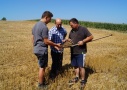Drei Personen diskutieren eine Spatenprobe auf einem abgeernteten Getreidefeld