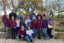 Personengruppe auf einer Kiesfläche vor Bäumen