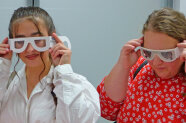 2 Frauen halten Papierbrille vor ihren Augen