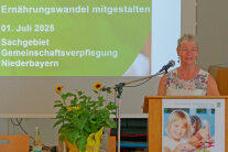 Frau steht am Rednerpult