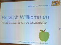 Leinwandprojektion mit Aufschrift "Herzlich Willkommen"