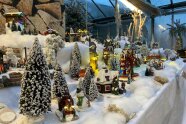 Winterliche Miniaturfiguren sind auf weißem Untergrund angeordnet.