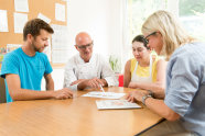 Zwei Männer und zwei Frauen sitzen um Tisch und schauen auf Blatt Papier © Tobias Hase, StMELF