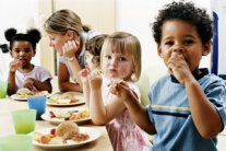 Kinder machen Brotzeit am Tisch