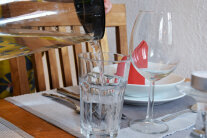 Glaskaraffe gießt Wasser in Glas auf einem gedeckten Tisch 