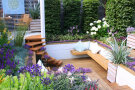 Gestaltete Terrasse mit Holzboden, Sitzgelegenheit und Bepflanzung 